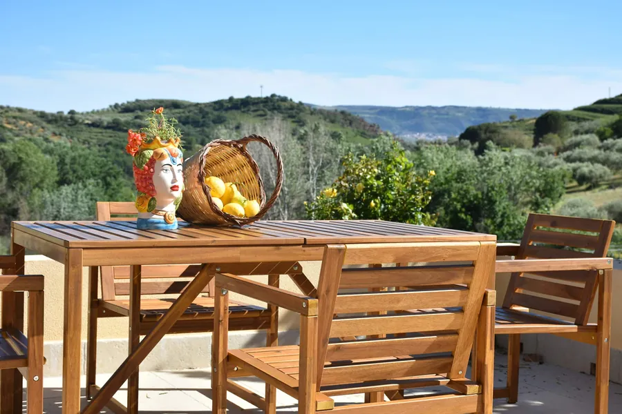 Il tavolo di legno in terrazza con la testa di moro, il cesto di limoni e le colline dietro