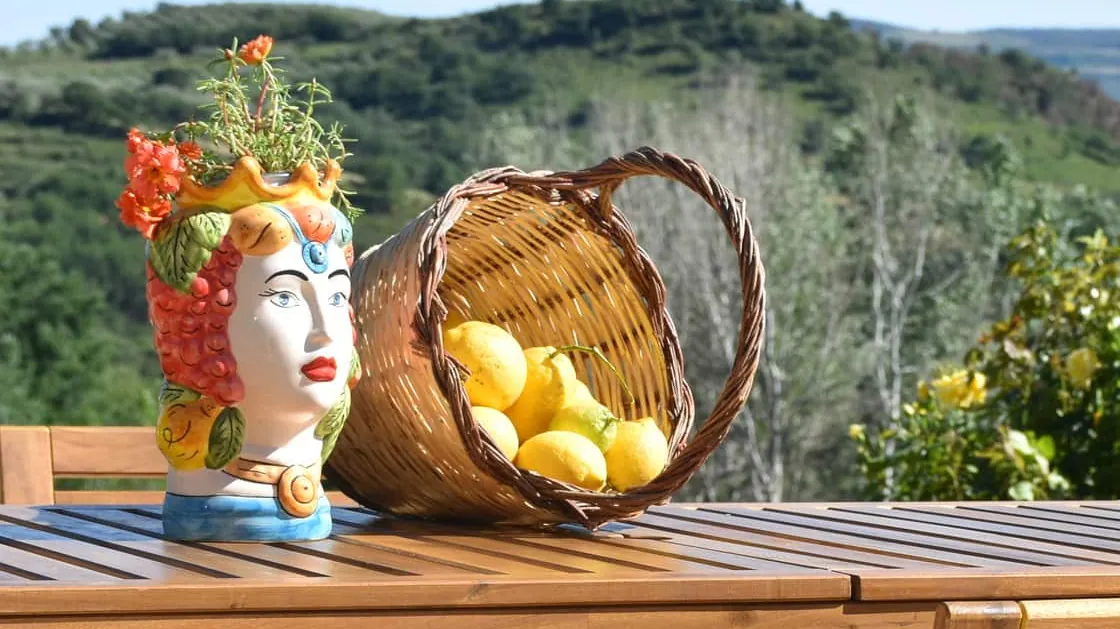 La testa di moro e il cesto di limoni sul tavolo di legno della terrazza, con le colline dietro